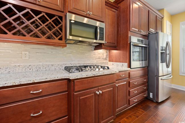 Kitchen featuring stainless steel appliances, baseboards, dark wood-style floors, and backsplash | Image 9