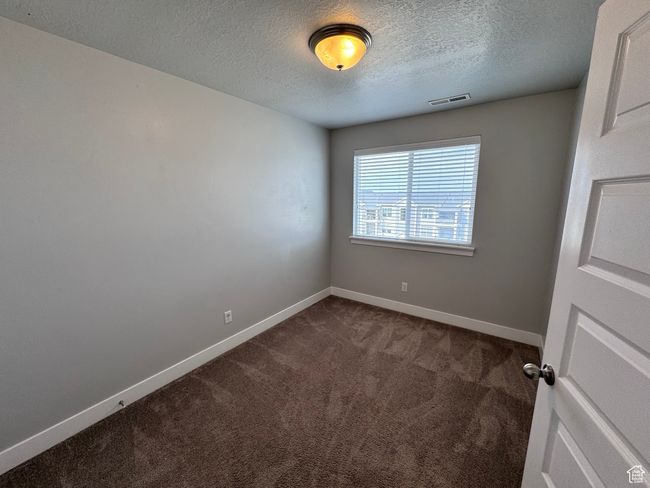 Spare room featuring dark colored carpet, a textured ceiling, visible vents, and baseboards | Image 19