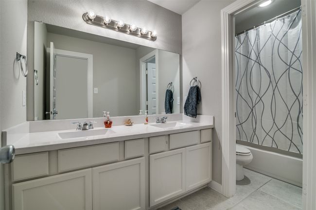 Full bath with double vanity, tile patterned floors, and shower / bath combination with curtain | Image 25