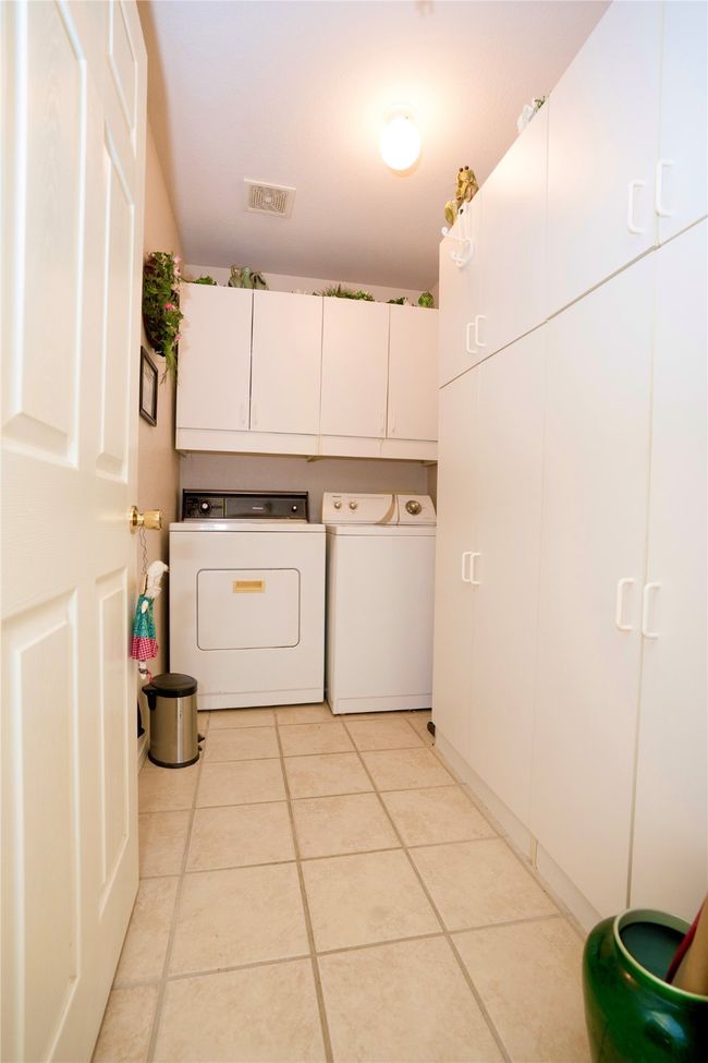 Laundry room featuring cabinet space, separate washer and dryer, and light tile patterned floors | Image 12