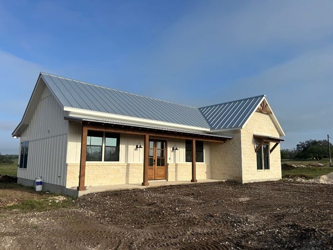 Modern inspired farmhouse featuring metal roof, stone siding, french doors, and board and batten siding | Image 6
