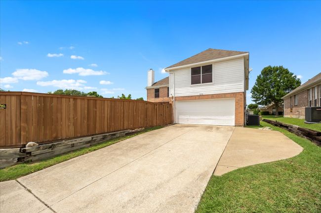 View of property exterior with central air condition unit, an attached garage, driveway, a shingled roof, and brick siding | Image 36