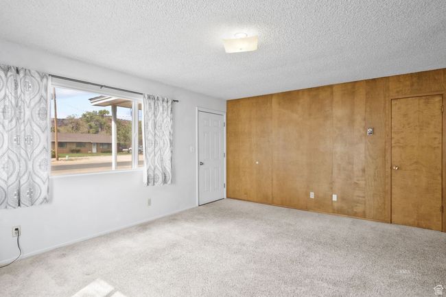 Carpeted spare room featuring wooden walls and a textured ceiling | Image 15