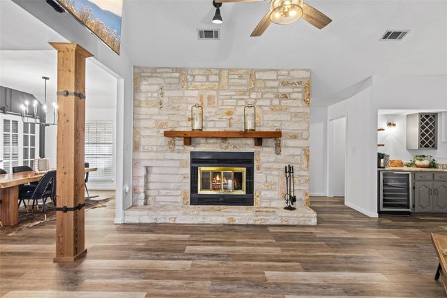 Living area featuring beverage cooler, ceiling fan, a dry bar, wood finished floors, and a fireplace | Image 12