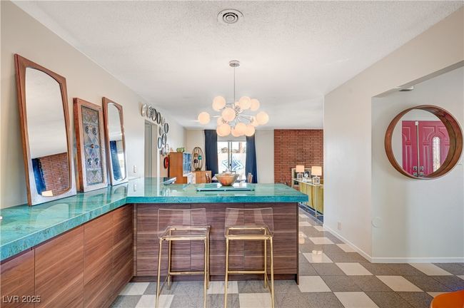 Bar featuring light floors, visible vents, an inviting chandelier, a textured ceiling, and baseboards | Image 15