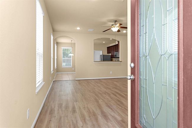 Step through the solid wood door featuring a large leaded glass window and be welcomed by an open, inviting floor plan. Luxurious vinyl plank flooring extends gracefully into the family room. | Image 4