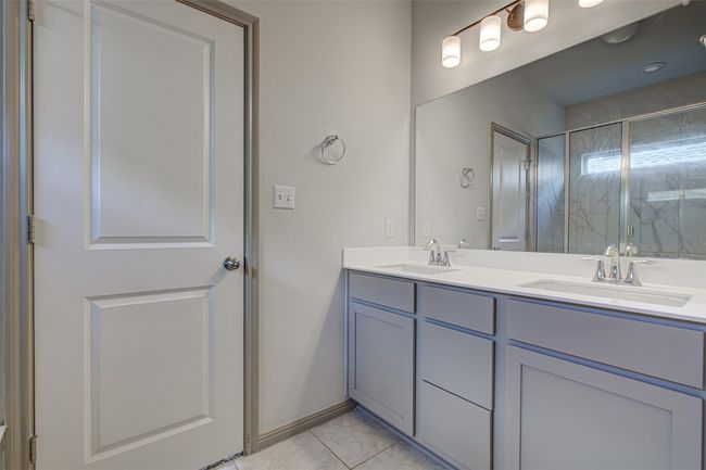 Bathroom featuring tile patterned floors, double vanity, and a shower with shower door | Image 18