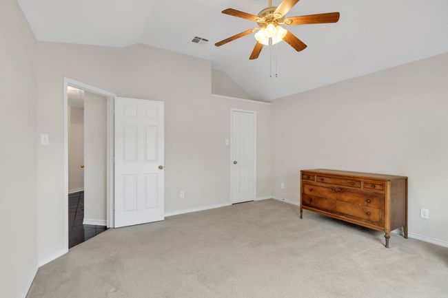 Unfurnished bedroom with lofted ceiling, visible vents, light carpet, baseboards, and ceiling fan | Image 32