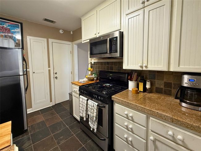 Kitchen with appliances with stainless steel finishes, decorative backsplash, and dark stone finish floors | Image 8