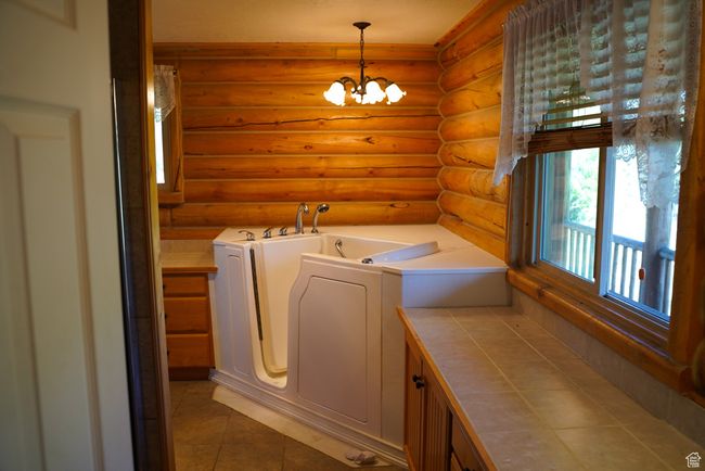Washroom featuring rustic walls, independent washer and dryer, a chandelier, and light tile patterned floors | Image 13