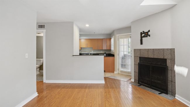 Kitchen featuring light wood-type flooring, baseboards, a fireplace, dark countertops, and recessed lighting | Image 6
