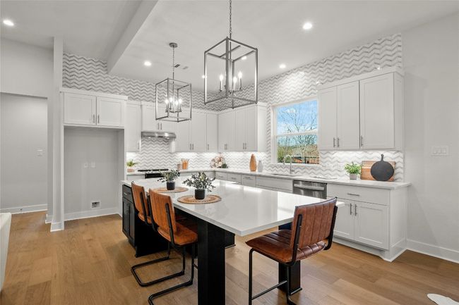 Kitchen featuring light countertops, a sink, a kitchen island, baseboards, and white cabinetry | Image 10
