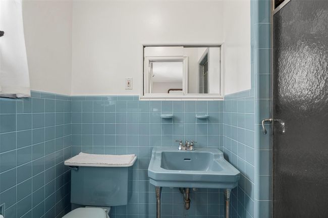 Main bathroom featuring tile walls, toilet, a sink, and wainscoting | Image 12