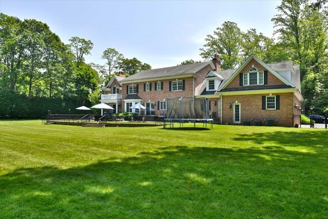 Back of house with a trampoline, a yard, a wooden deck, and brick siding | Image 33