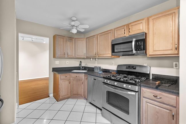 Kitchen featuring stainless steel appliances, a sink, light brown cabinets, and dark countertops | Image 9