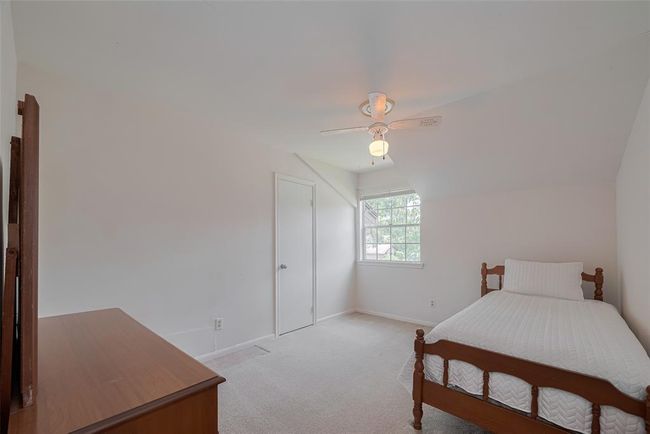 Cozy fourth bedroom with natural light, featuring a charming sloped ceiling and ample space for relaxation. | Image 26