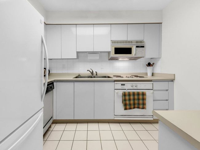Kitchen featuring white appliances, a sink, light countertops, white cabinetry, and backsplash | Image 9