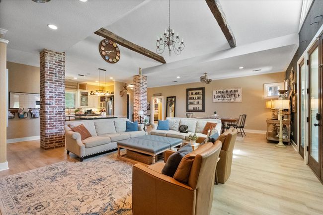 Living area with ornate columns, recessed lighting, light wood-style floors, beam ceiling, and a chandelier | Image 6