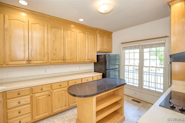 Kitchen featuring light floors, black appliances, light brown cabinetry, and open shelves | Image 11