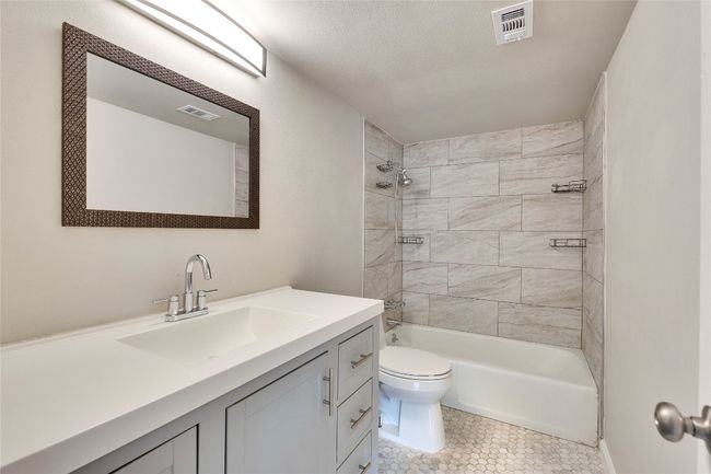 Full bathroom in-between secondary bedrooms thats been updated with vanity, light fixture, and tile in shower. | Image 25