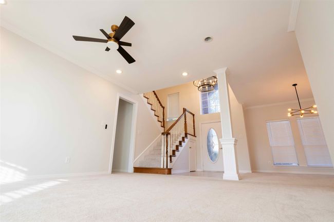 Foyer entrance featuring crown molding, a chandelier, stairs, light colored carpet, and a ceiling fan | Image 4
