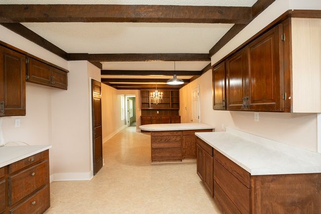 Kitchen with light flooring, light countertops, beam ceiling, decorative light fixtures, and a chandelier | Image 16
