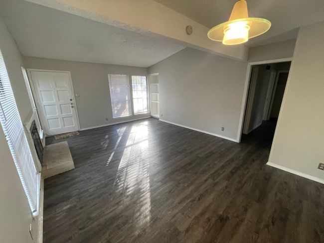 Unfurnished living room featuring dark wood-style flooring and a fireplace | Image 5