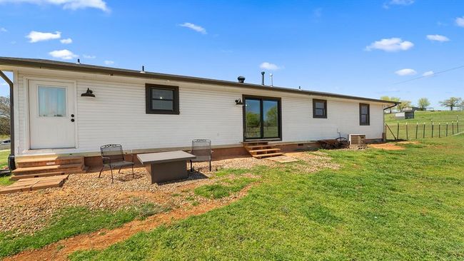 Rear view of house featuring central air condition unit, entry steps, fence, and a lawn | Image 13