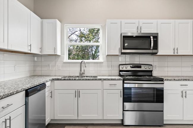 Kitchen with white cabinetry, sink, and appliances with stainless steel finishes | Image 12