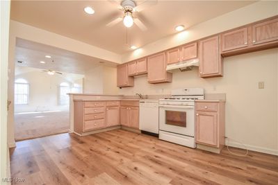 Kitchen featuring light hardwood / wood-style flooring, ceiling fan, light brown cabinetry, and white appliances | Image 3