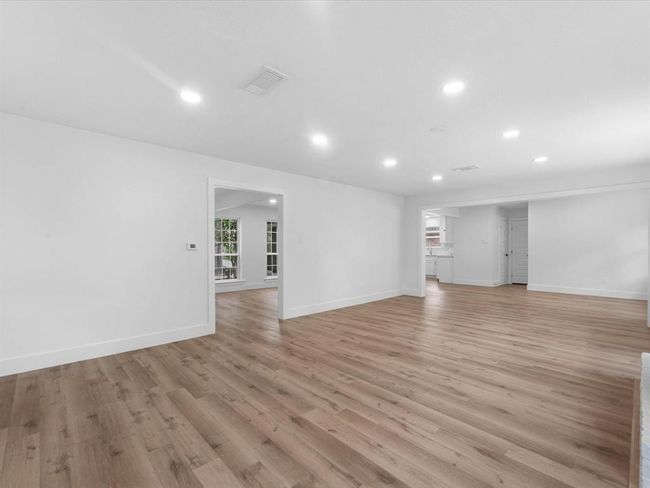 Spacious open-concept living area with sleek hardwood floors and recessed lighting, featuring a seamless flow into adjacent rooms and plenty of natural light. | Image 8