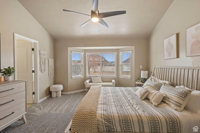 Carpeted bedroom with a textured ceiling, vaulted ceiling, and ceiling fan | Image 10