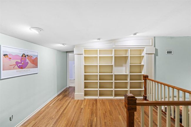 Versatile upstairs nook, ideal for a chic home office or cozy lounge space, complete with built-in shelving. | Image 7