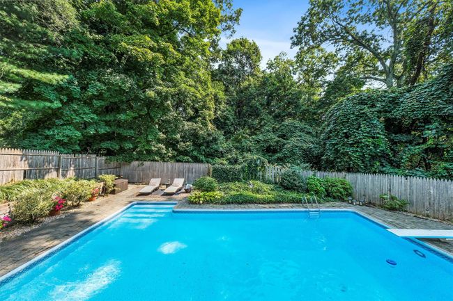 View of swimming pool with a diving board, a fenced in pool, and a fenced backyard | Image 44