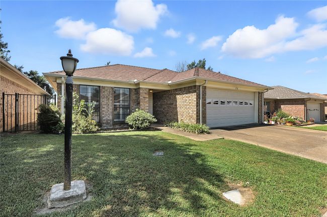 Single story home with a garage, brick siding, roof with shingles, and concrete driveway | Image 4