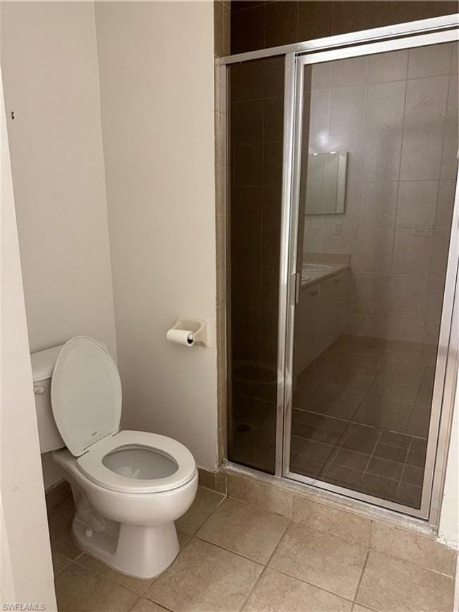 Bathroom with toilet, tile patterned floors, and a shower with door | Image 14