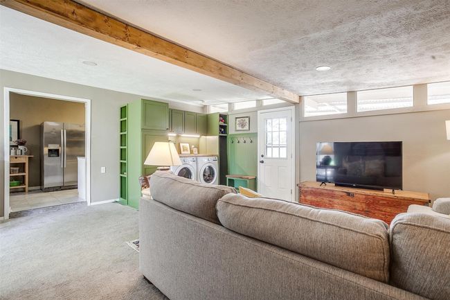Living room with washing machine and clothes dryer, light carpet, beamed ceiling, and a textured ceiling | Image 24