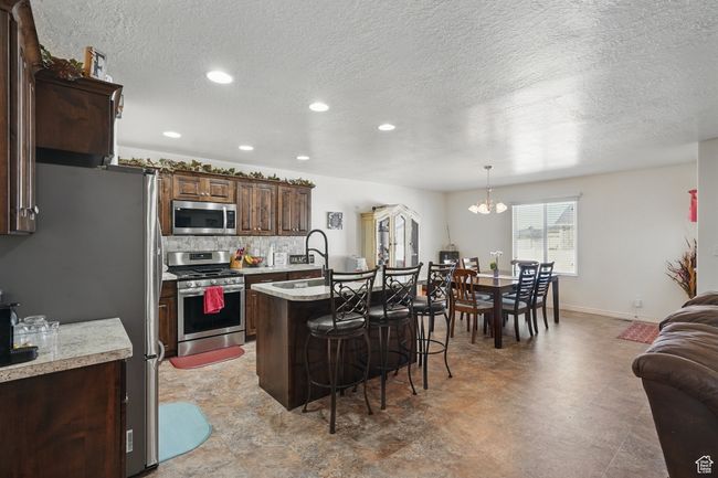 Kitchen featuring open floor plan, light countertops, a breakfast bar area, appliances with stainless steel finishes, and a sink | Image 15