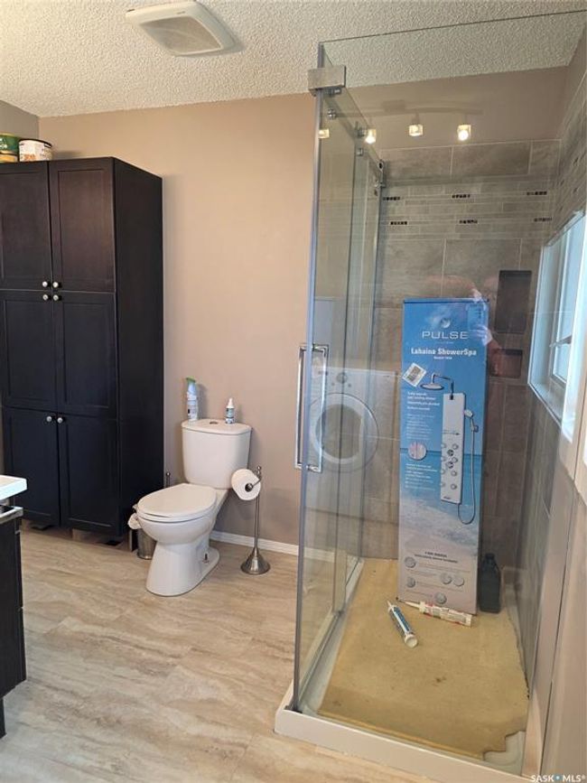 Bathroom featuring a textured ceiling, vanity, toilet, and a stall shower | Image 20