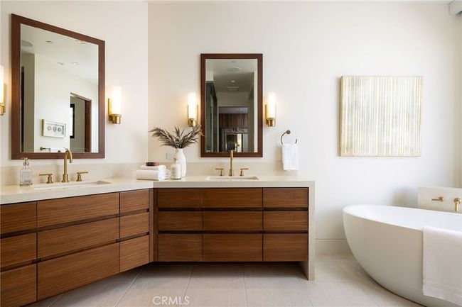 The spa-inspired primary bath features quartzite surfaces, steam shower, freestanding jacuzzi tub, and custom walnut cabinetry. | Image 15