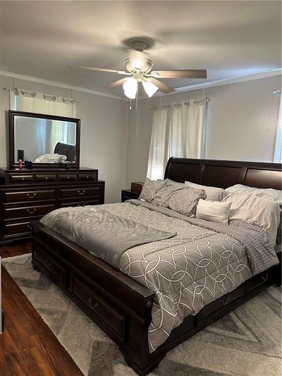 Bedroom featuring hardwood / wood-style flooring, crown molding, and ceiling fan | Image 3