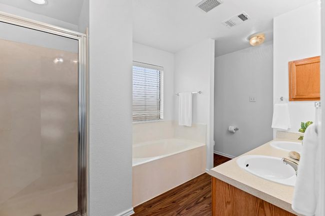 Bathroom with a garden tub, wood finished floors, a stall shower, and double vanity | Image 30