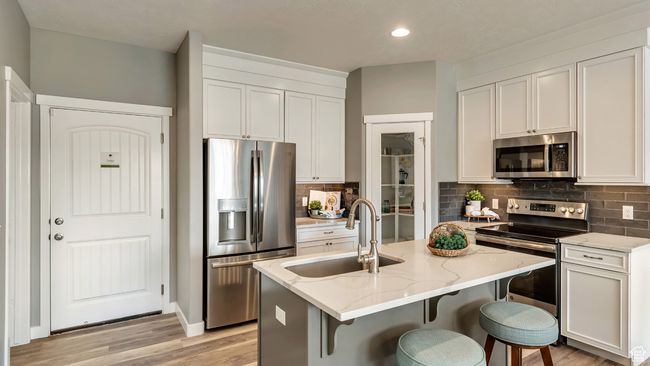 Kitchen featuring tasteful backsplash, light stone countertops, stainless steel appliances, and a sink | Image 5