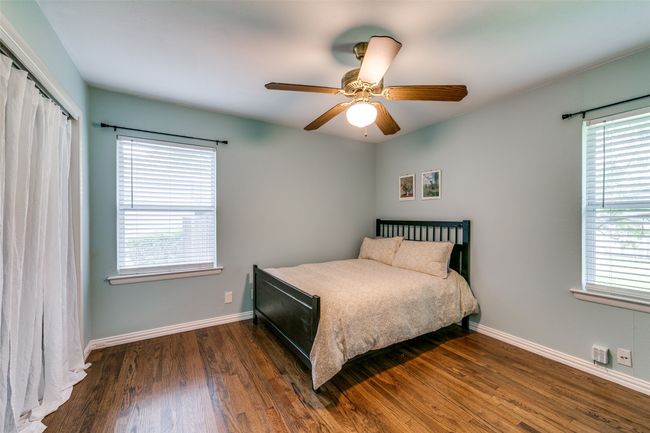 Bedroom with wood finished floors, multiple windows, a closet, and a ceiling fan. | Image 16
