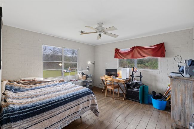 Bedroom featuring ceiling fan, ornamental molding, brick wall, and wood-type flooring | Image 8