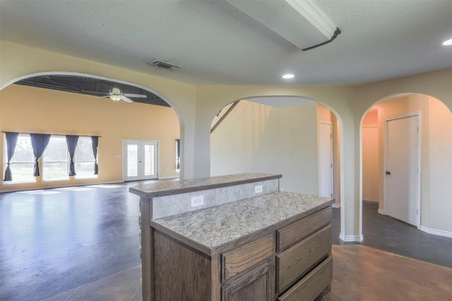 Kitchen featuring light countertops, a center island, visible vents, and finished concrete flooring | Image 9