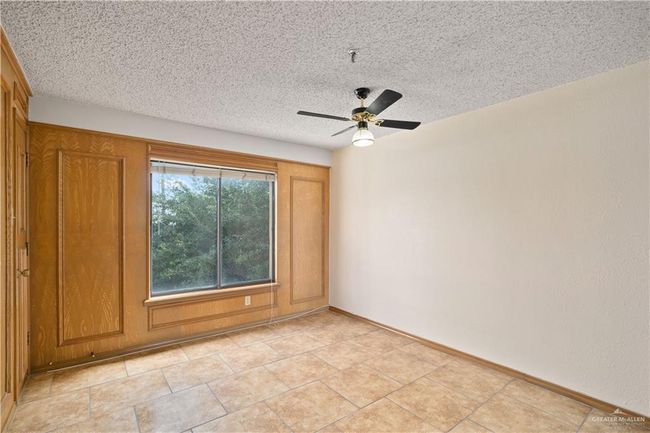 Spare room with a ceiling fan, a textured ceiling, a pendent fire sprinkler, and light tile patterned flooring | Image 12