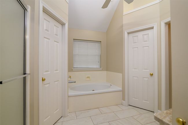 Full bath featuring lofted ceiling, a garden tub, ceiling fan, a shower with door, and tile patterned flooring | Image 14