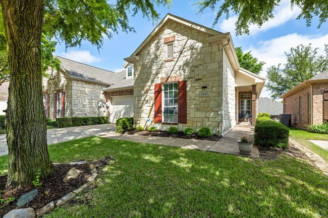 Traditional home featuring stone siding, driveway, a front yard, central AC, and a garage | Image 32