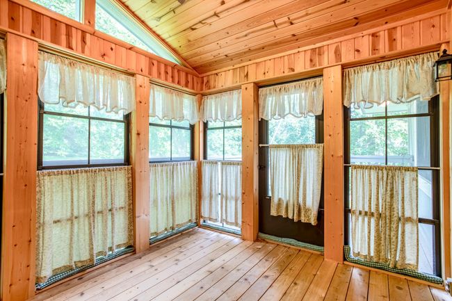 Charming 3-season porch wrapped in windows and natural wood, offering a relaxing retreat with serene views. | Image 13